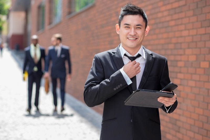 Man in suit smiling and adjusting his tie 