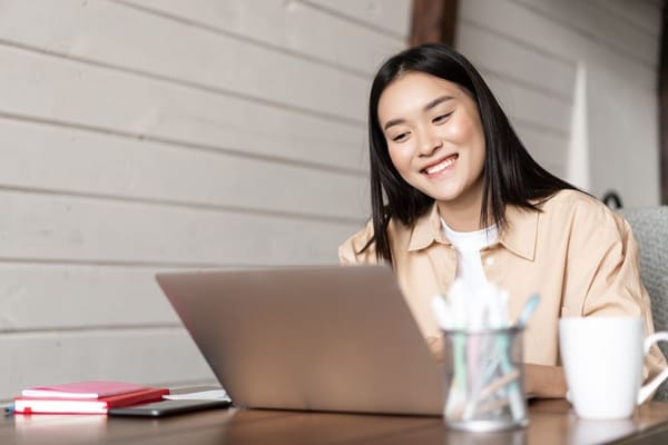 Woman smiling in front of a laptop at a desk 