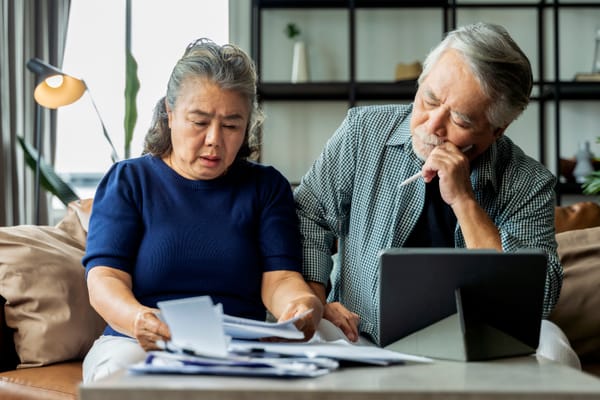 Couple looking at bills with a puzzled expression.